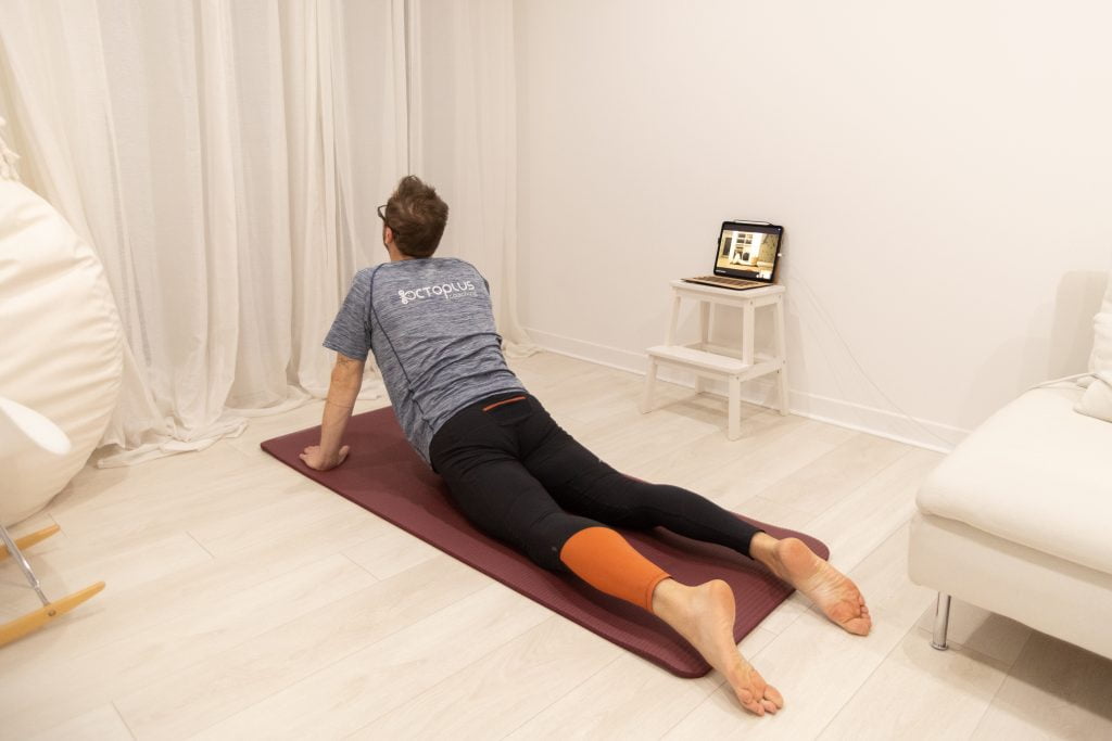 Homme faisant du yoga devant un ordinateur.