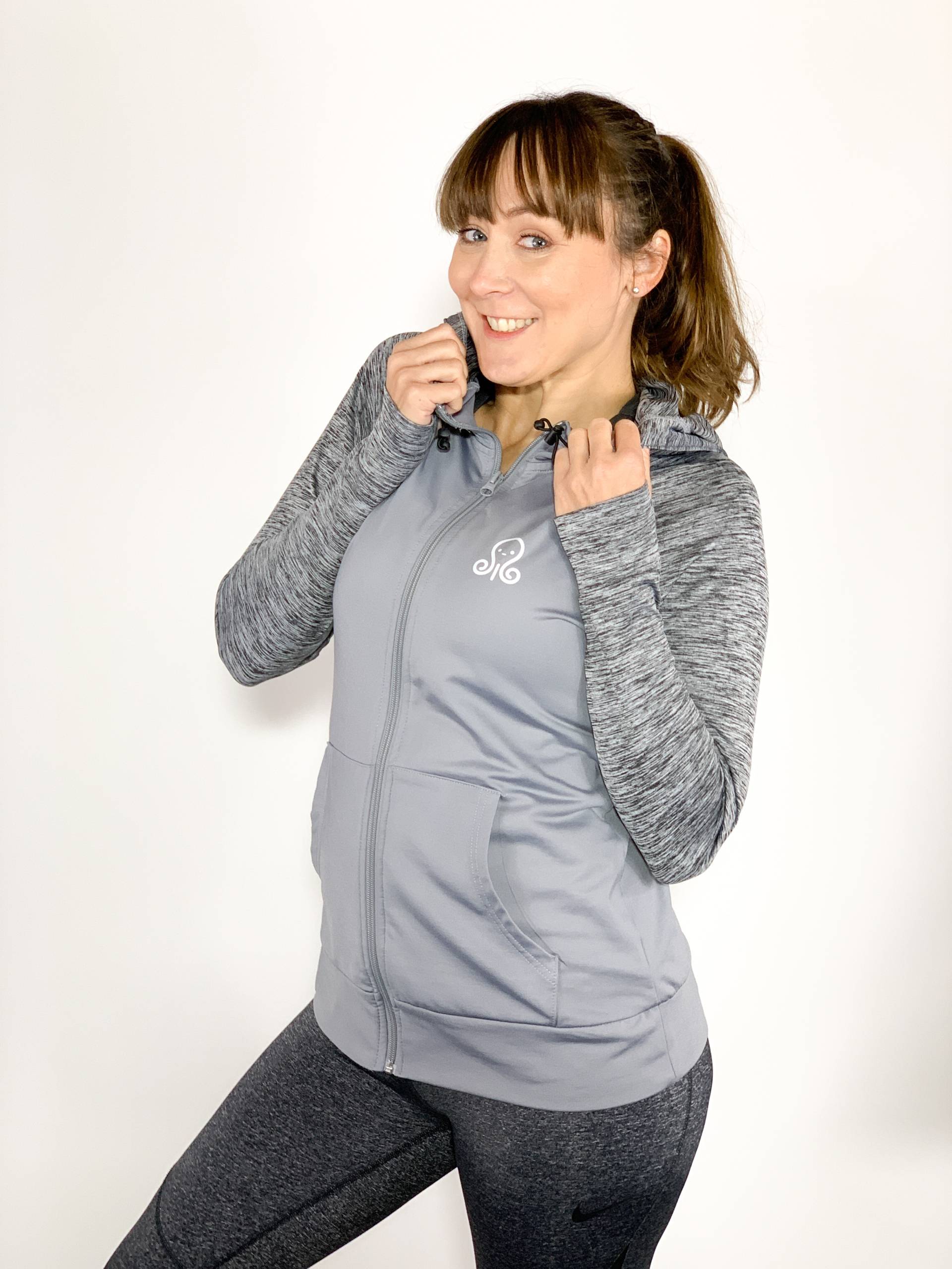 Femme souriante en tenue de sport grise.