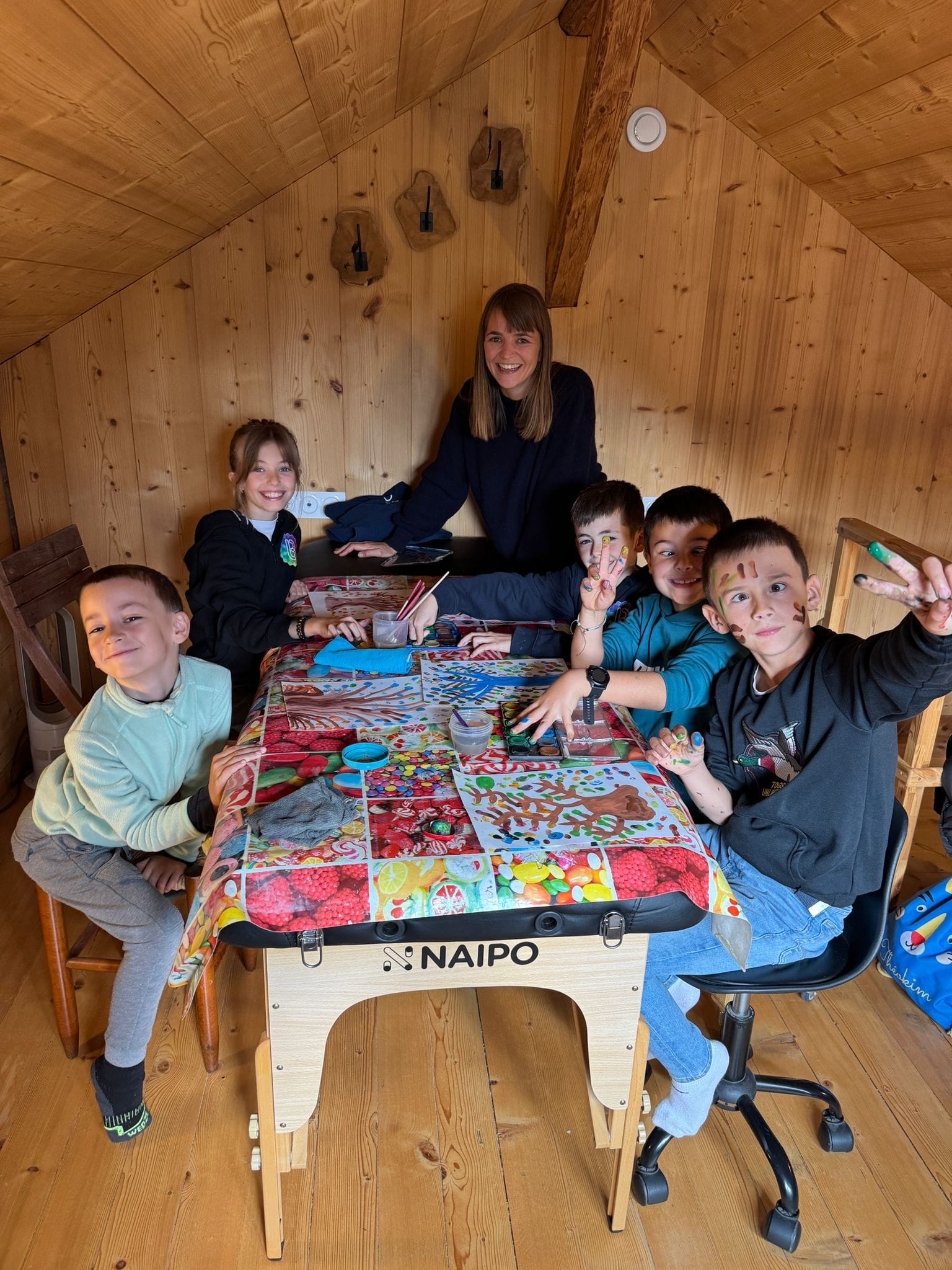 Enfants et adulte souriant autour d'une table de jeu.