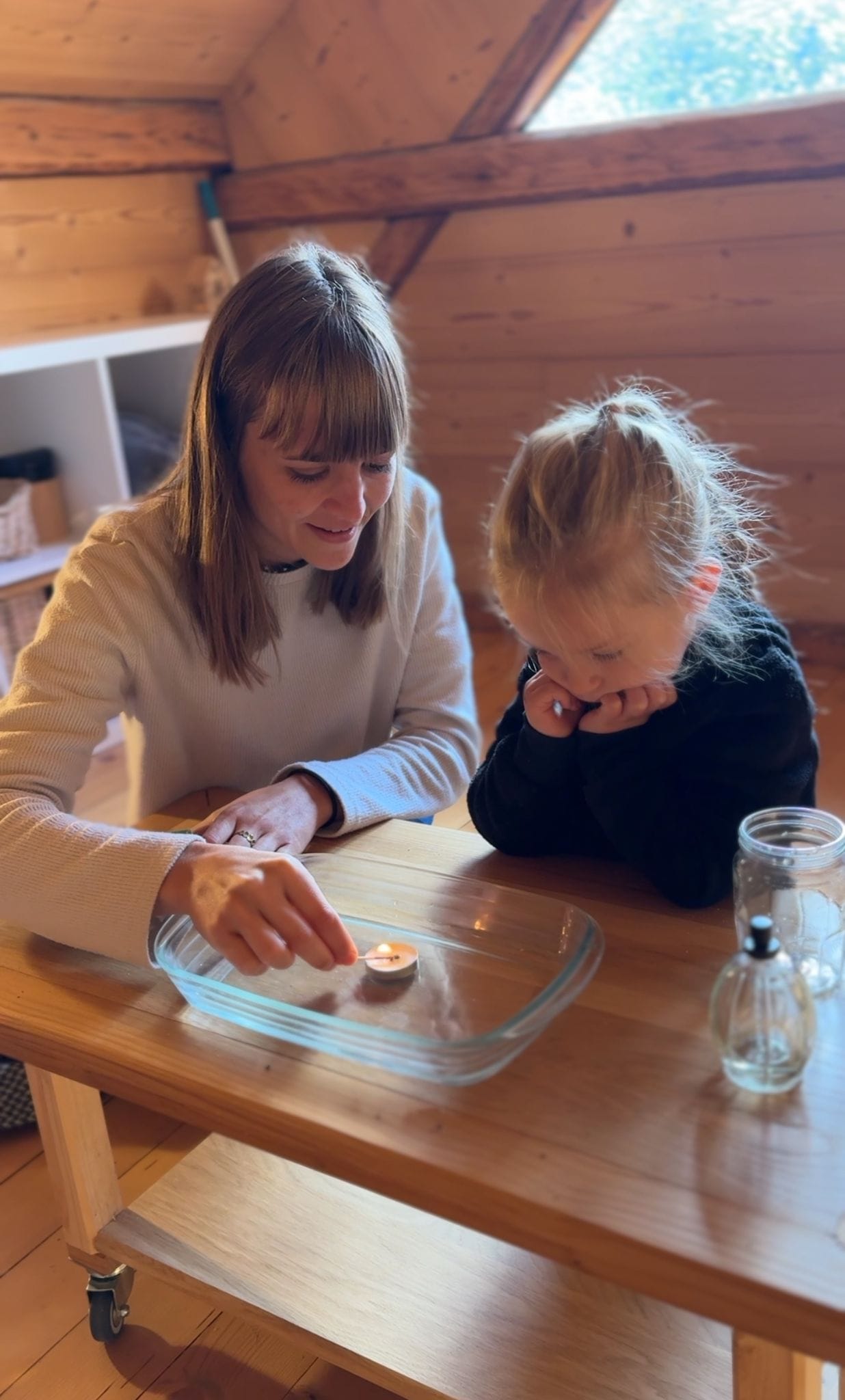 Enfant et adulte allumant une bougie.