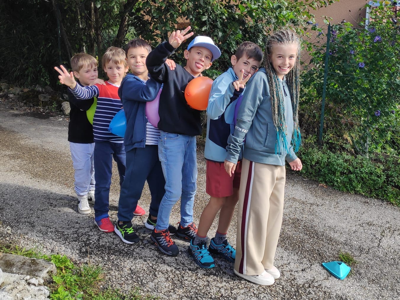 Enfants en file avec des ballons colorés.