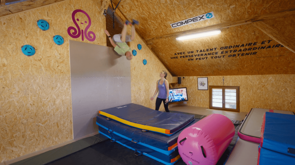 Personnes s'entraînent dans un gymnase intérieur sur un trampoline.