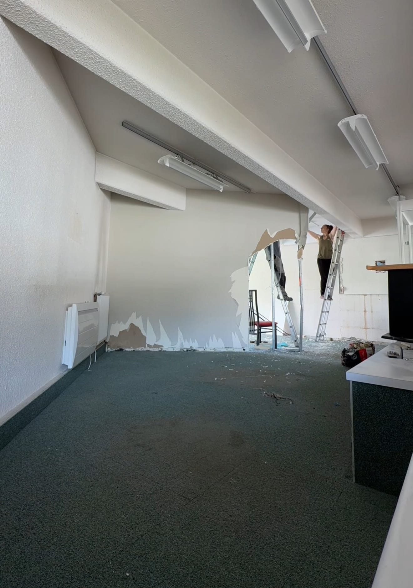 Travailleurs démolissant un mur intérieur.