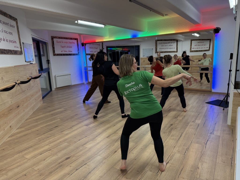 Cours de danse en studio avec miroirs et éclairage coloré.