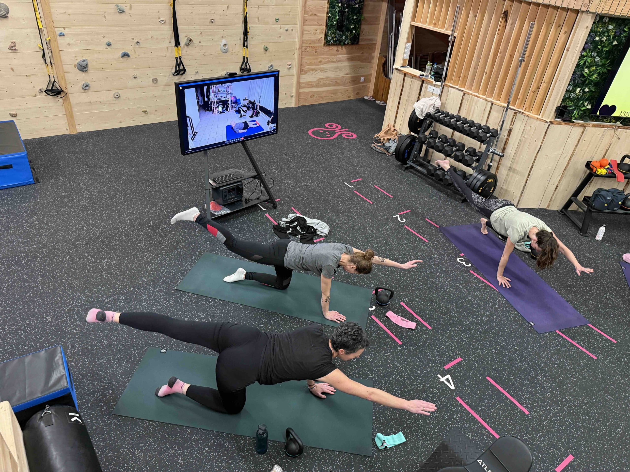 Personnes faisant du yoga avec écran et haltères.