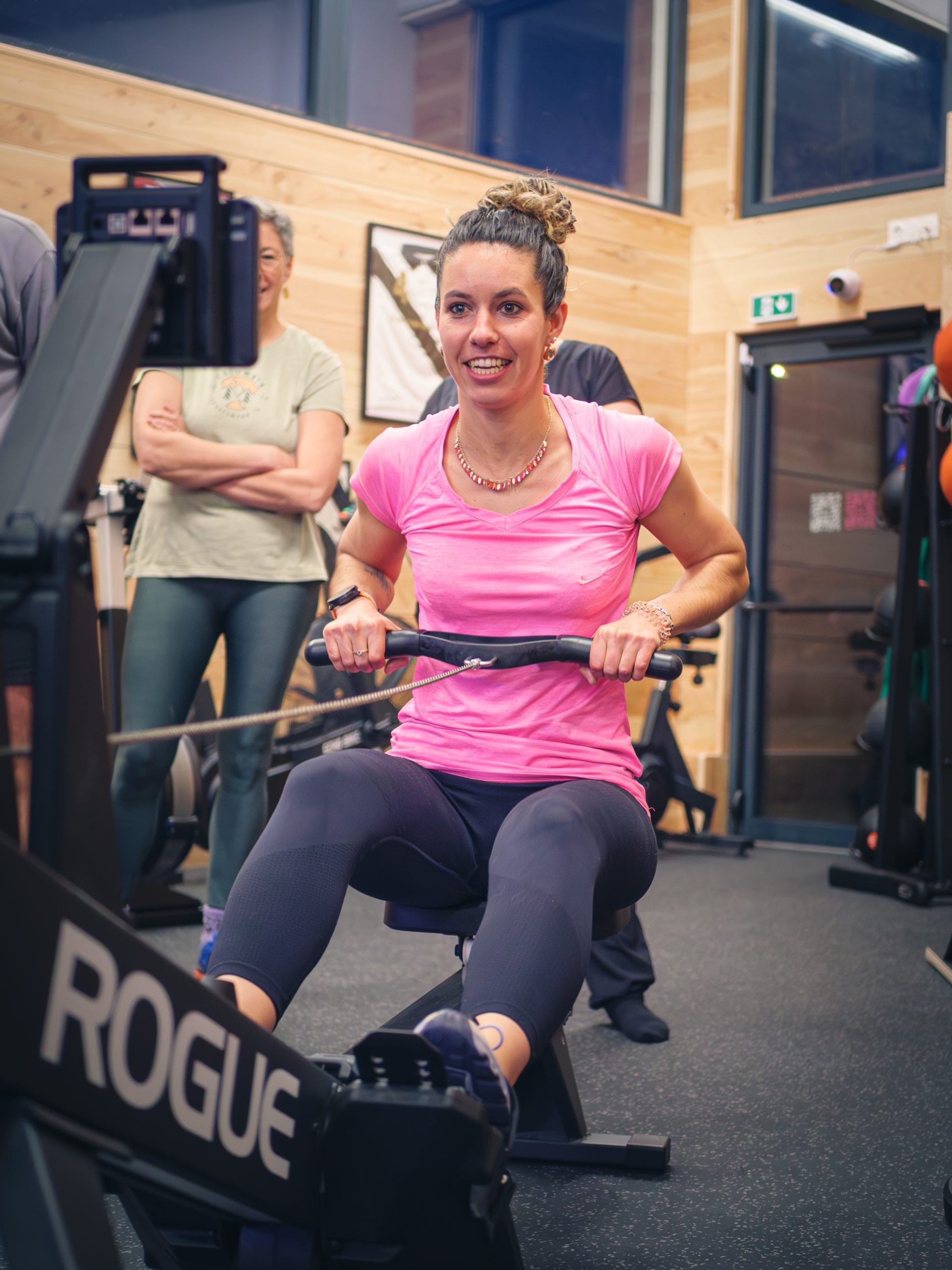 Femme s'entraînant sur rameur en salle de sport.