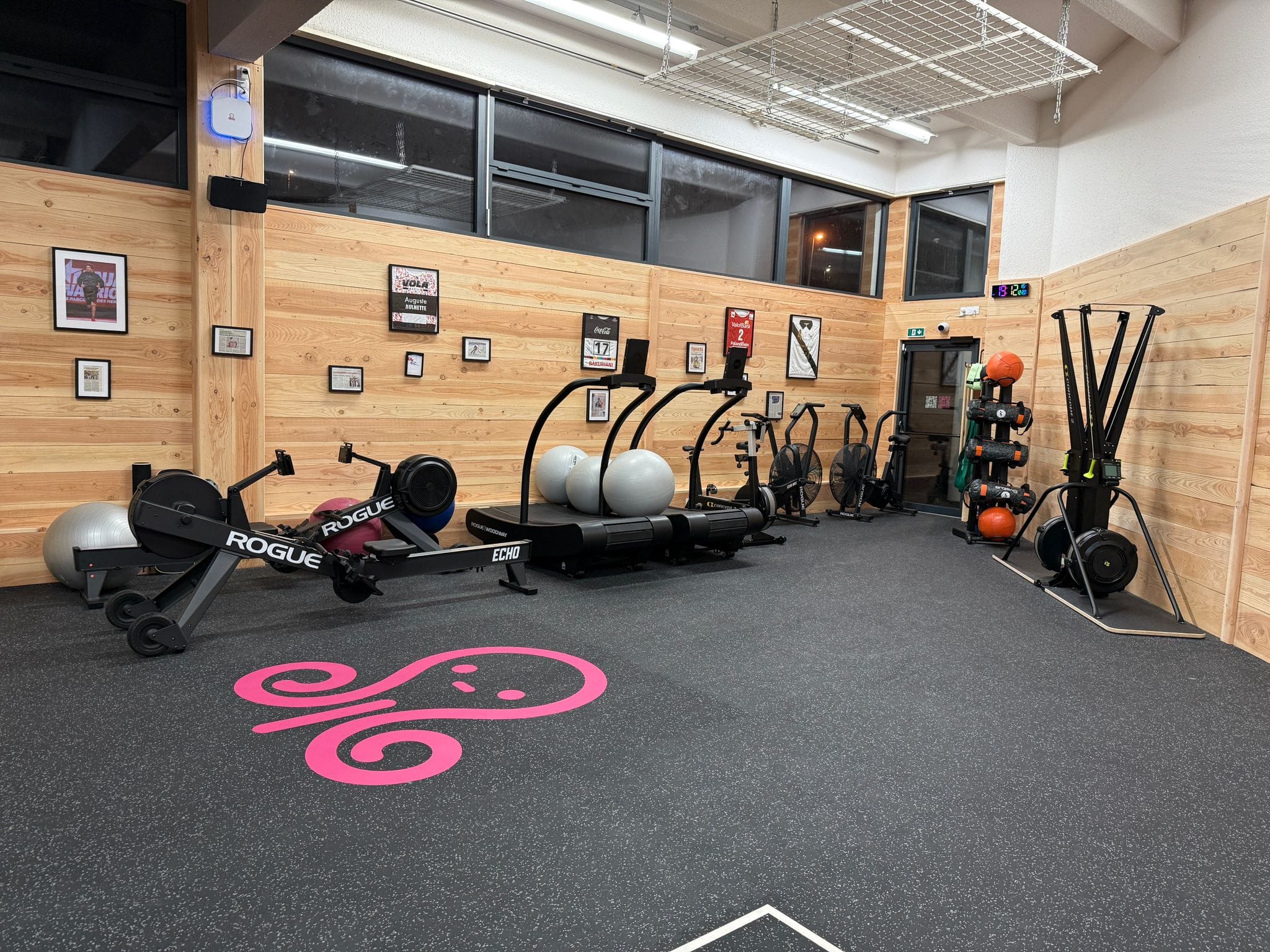 Salle de sport avec équipements et murs boisés.