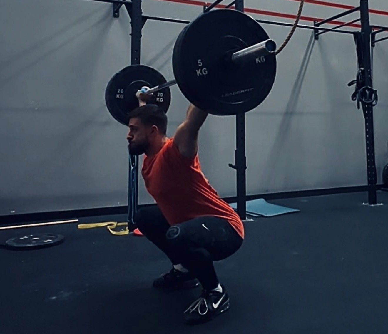 Homme en squat avec haltères dans une salle
