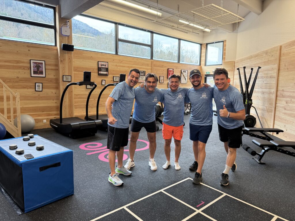 Cinq hommes souriants dans une salle de sport