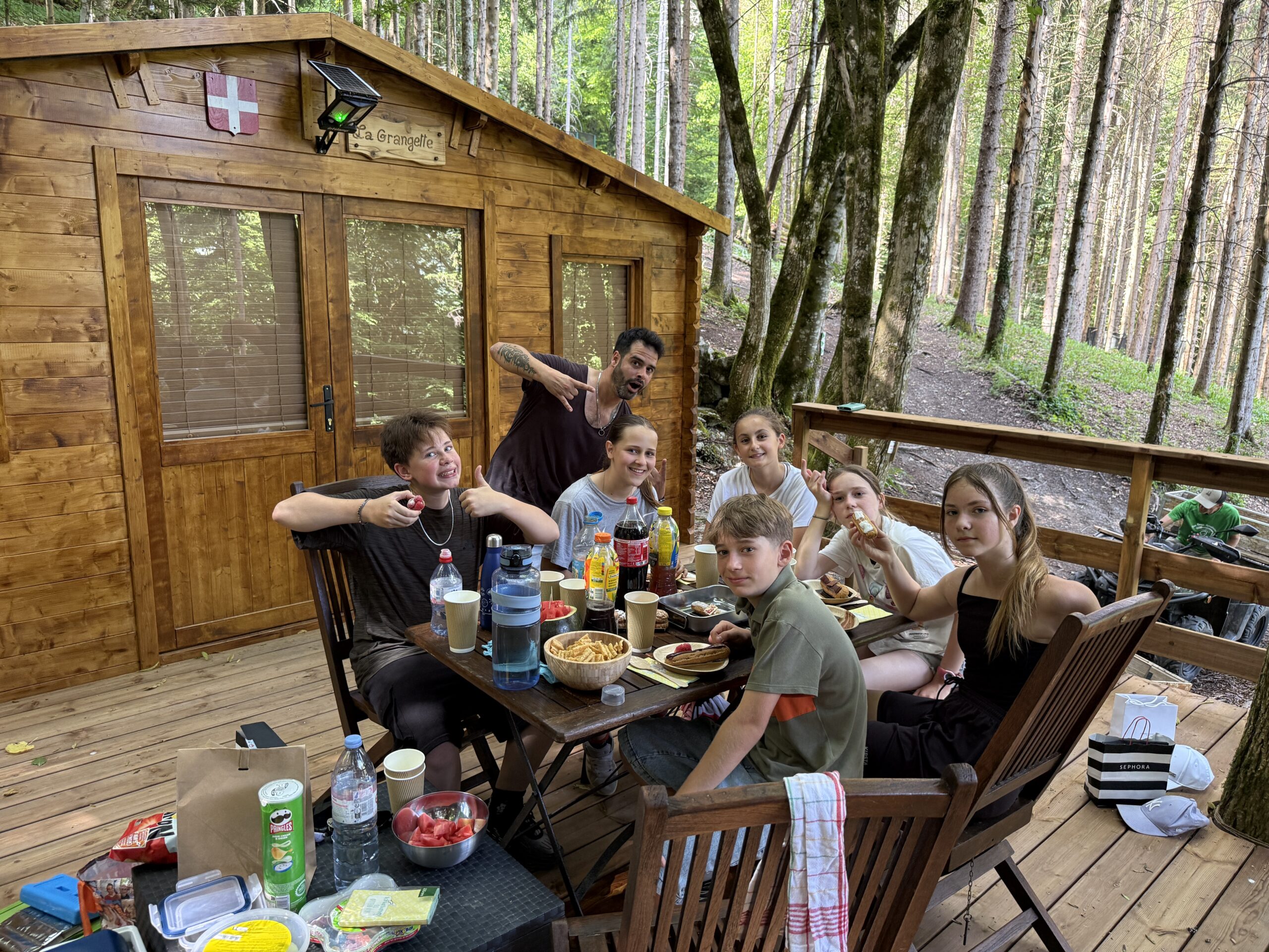 Groupe d’adolescents déjeunant devant chalet en forêt